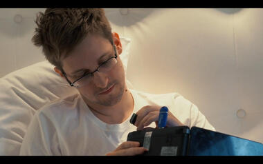 Snowden steckt eine SD-Karte in einen Laptop mit einem blauen Tails-USB-Stick